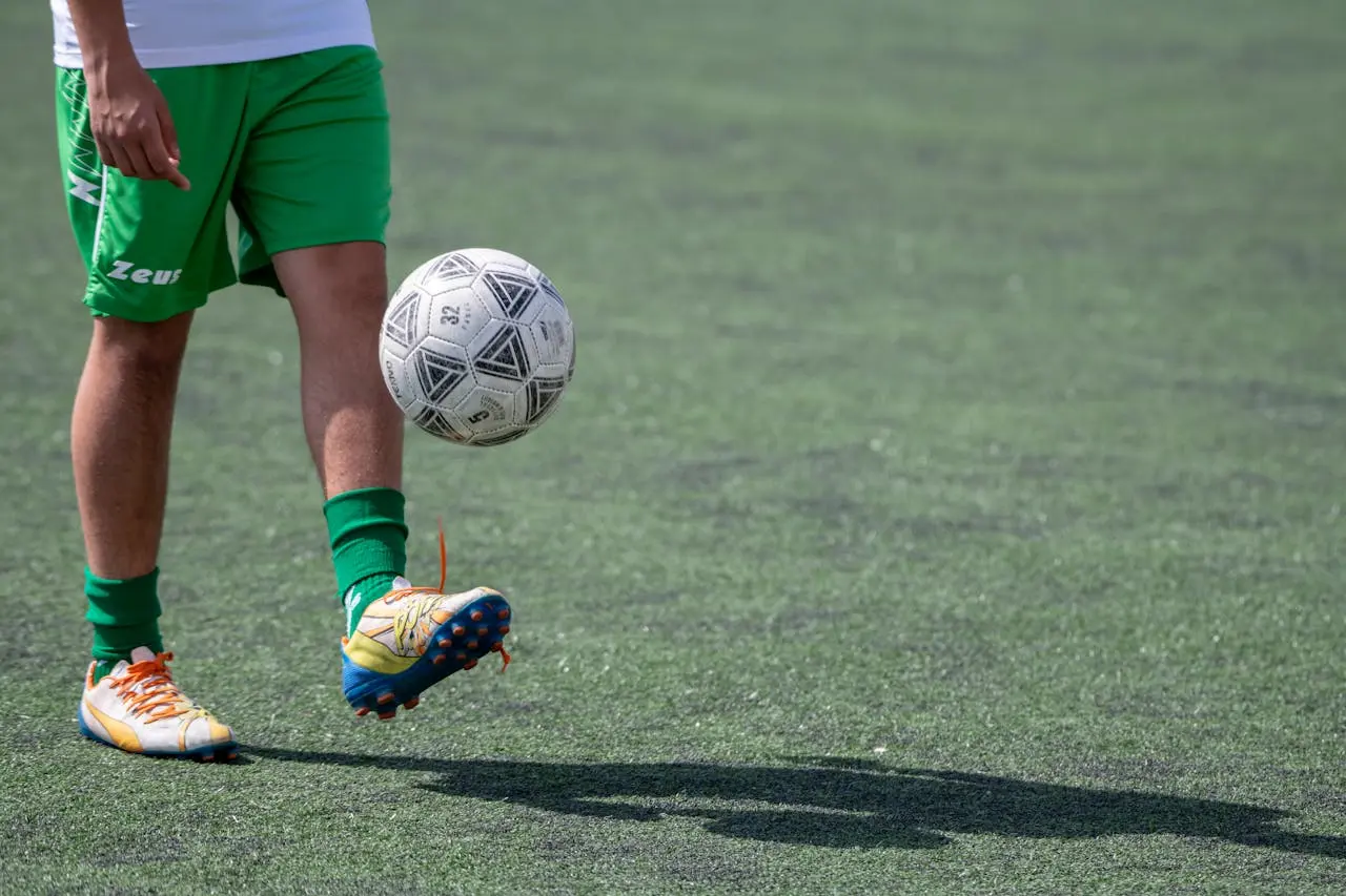 Young soccer player juggling a ball alone outdoors